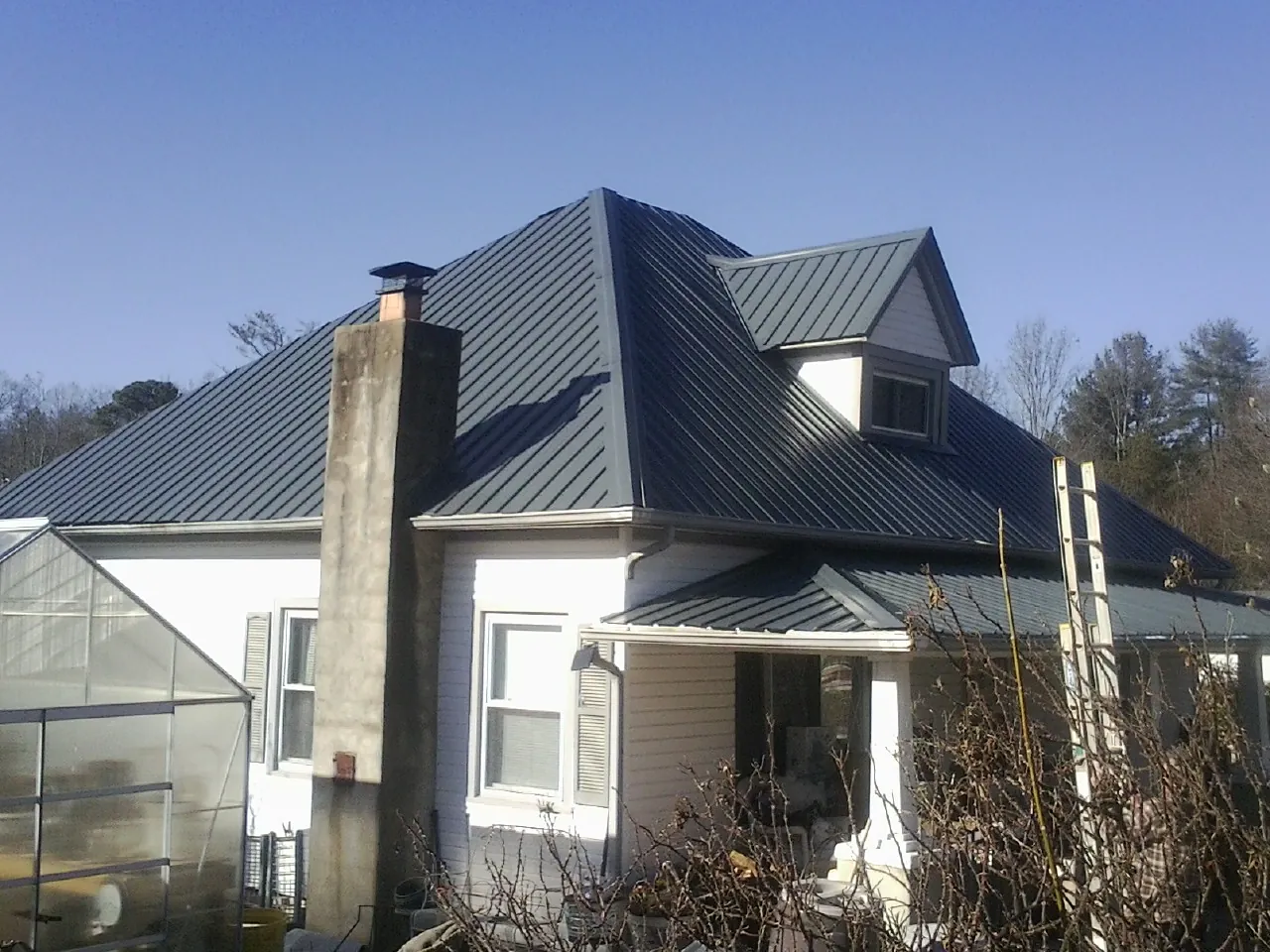 Dark blue standing seam metal roof on a white farmhouse with dormer — Slate & Tile Roof Repair by Roofing Brothers in Pawtucket
