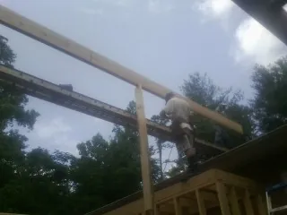 Carpenter setting a ridge beam over a new addition frame — Ice Dam Removal by Roofing Brothers in Pawtucket