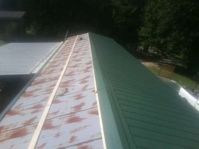 Old rusted panels beside newly installed green metal roofing — Wind Damage Roof Repair by Roofing Brothers in Pawtucket
