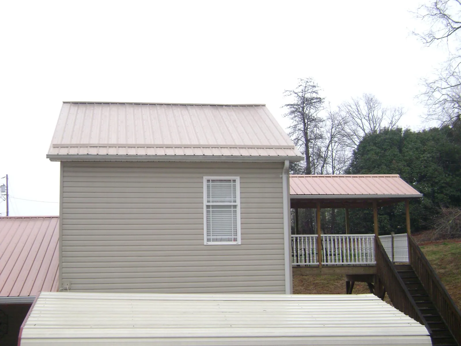 Tan metal roofs on a two story addition and attached porch, from a Roof Replacement job in Pawtucket